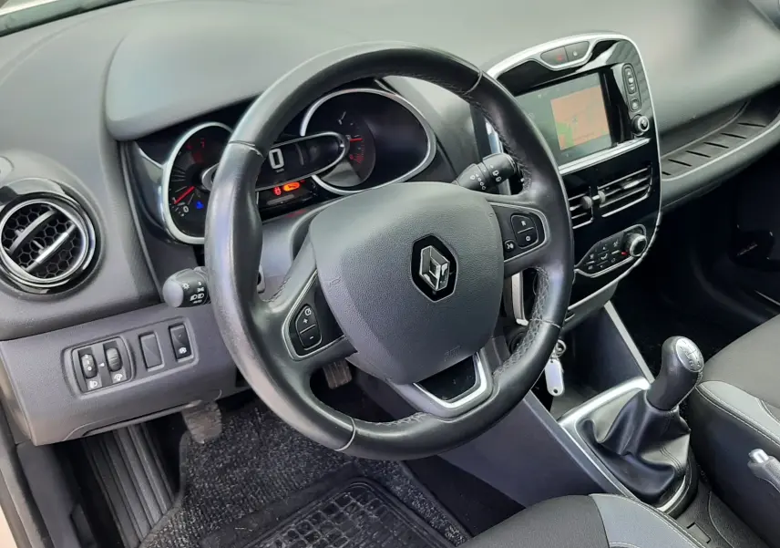 Vue intérieure centrée sur le volant et la console centrale d'une Renault Clio IV Estate beige, avec boîte manuelle et écran tactile.