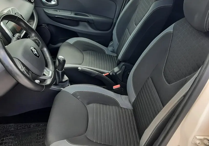 Vue intérieure côté conducteur de la Renault Clio IV Estate beige, avec sièges tissu noir et volant multifonction.
