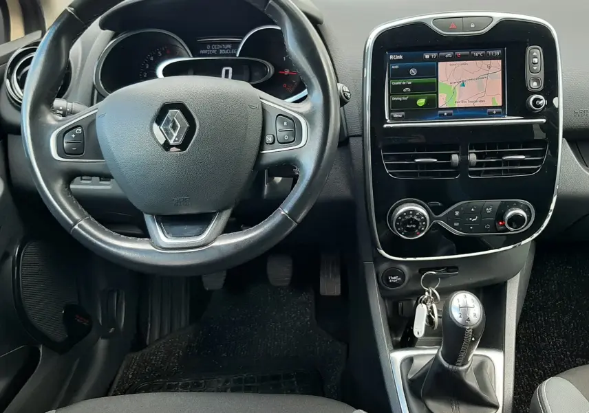Vue intérieure centrée sur le volant noir et la console centrale avec écran tactile de la Renault Clio IV beige de 2016.