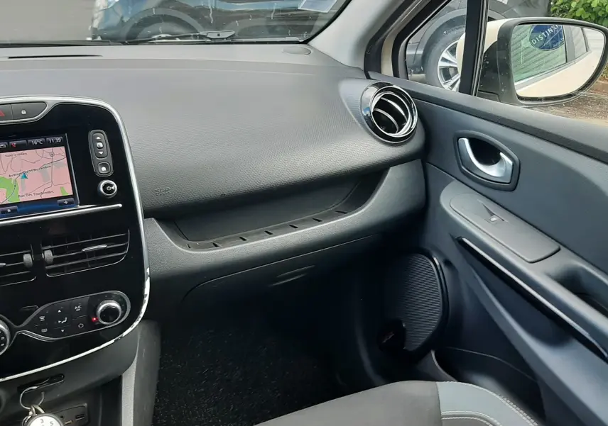Vue intérieure côté passager de la Renault Clio IV Estate beige, montrant tableau de bord et console centrale avec navigation.