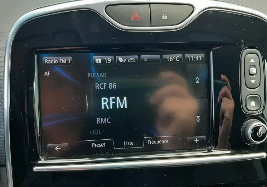 Écran tactile central de la Renault Clio IV Estate beige, affichant la radio FM avec commandes autour en vue frontale.