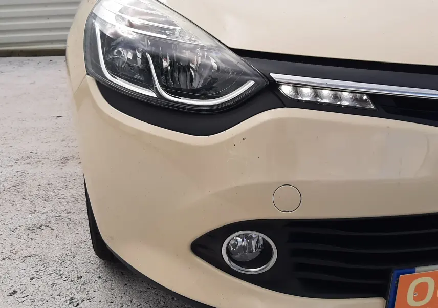 Gros plan sur l'avant gauche beige d'une Renault Clio IV Estate avec phares LED et antibrouillard visibles.
