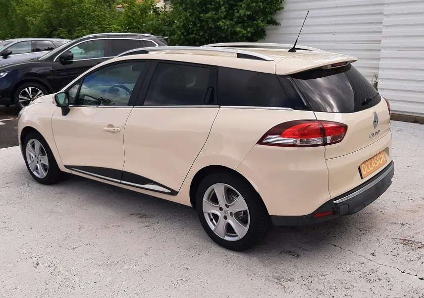 Renault Clio IV Estate beige vue 3/4 arrière droit, avec vitres arrière teintées et jantes alliage 16 pouces.