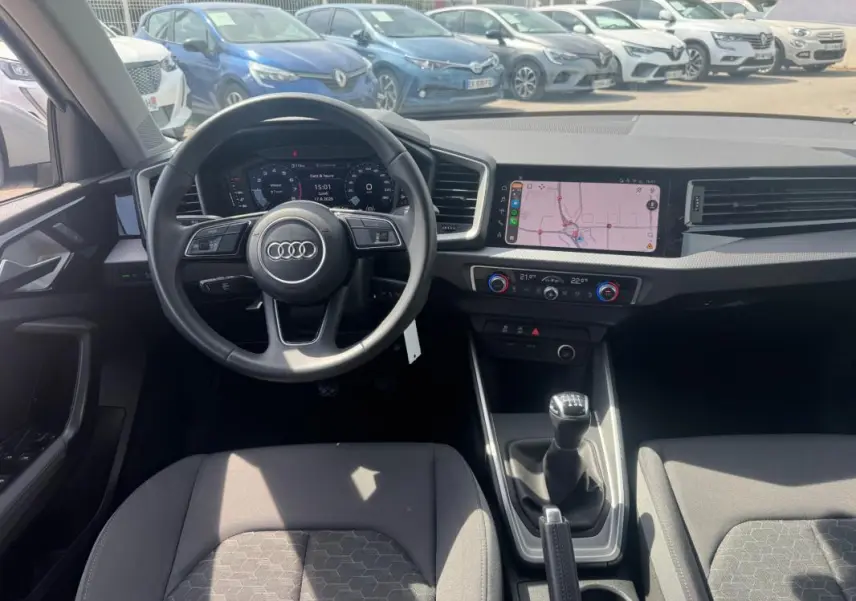Vue intérieure avant de l'Audi A1 Sportback gris 2025, volant cuir, cockpit numérique et écran tactile avec navigation.