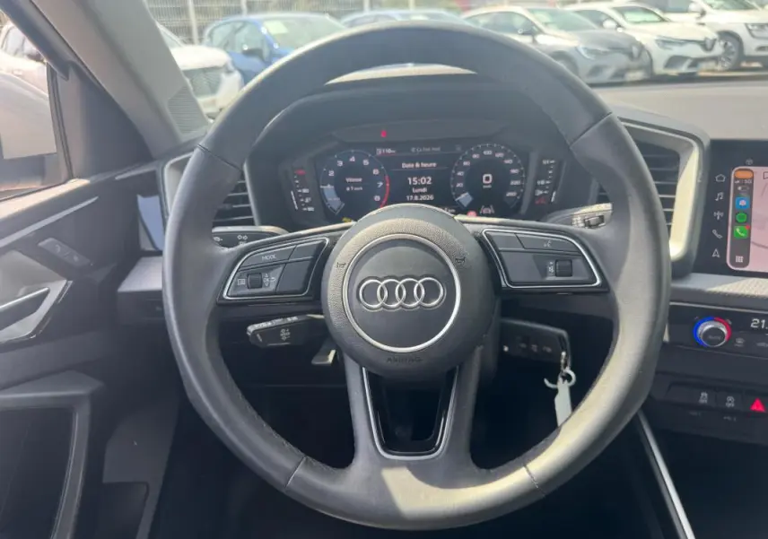 Vue intérieure centrée sur le volant cuir noir d’une Audi A1 Sportback 2025 avec cockpit numérique et console multimédia.