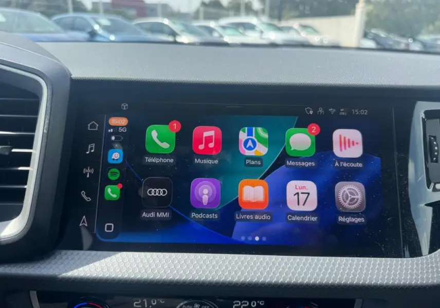 Écran tactile central de l’Audi A1 Sportback 2025 affichant les applications multimédia, avec tableau de bord gris en arrière-plan.