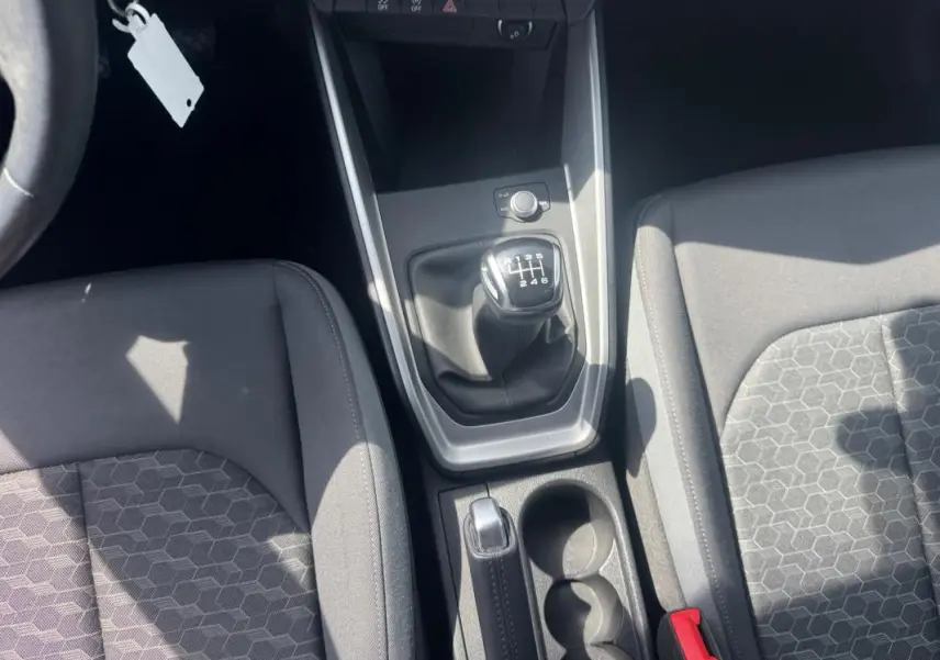 Vue intérieure centrée sur la console centrale d'une Audi A1 Sportback 2025 avec boîte manuelle et sièges sport gris.