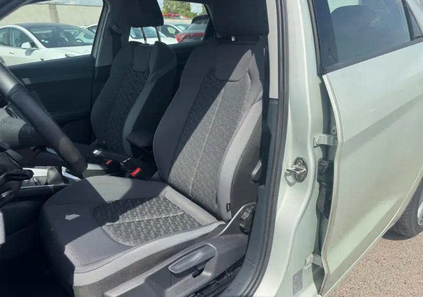 Vue intérieure côté conducteur de l'Audi A1 Sportback 2025 gris, mettant en valeur les sièges sport et l'accoudoir central.
