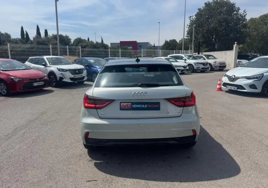 Vue arrière d'une Audi A1 Sportback gris clair 2025 avec feux LED et vitre arrière teintée, stationnée en extérieur.