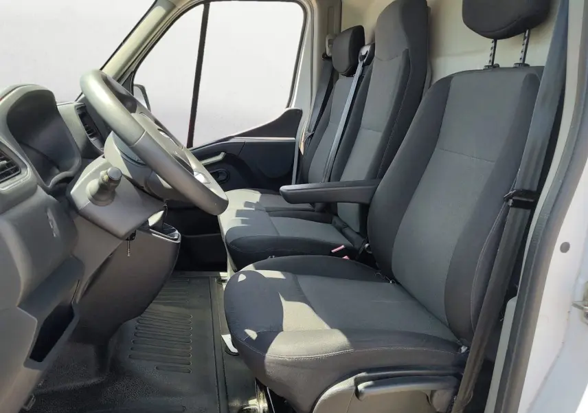Intérieur du Renault Master blanc 2022 vu de côté gauche, montrant les trois sièges avant en tissu noir et le volant.