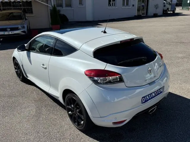 Renault Mégane III Coupé 2.0T 265cv RS blanc nacré vue 3/4 arrière droit avec jantes noires et vitres teintées.