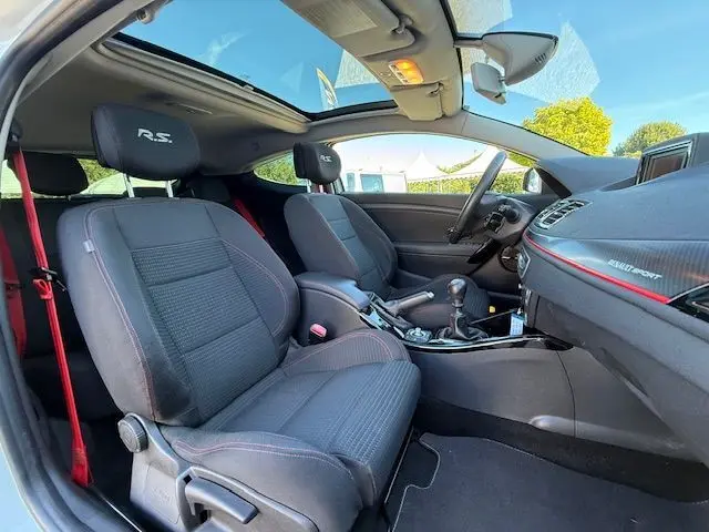 Intérieur de la Renault Mégane III Coupé RS blanc nacré, vue côté droit, sièges tissu avec logo R.S. et toit ouvrant.