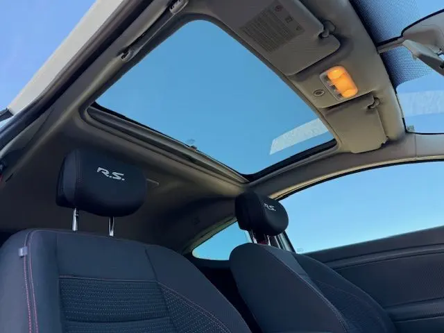 Vue intérieure du toit ouvrant panoramique et des sièges noirs avec logo R.S. de la Renault Mégane III Coupé Blanc Nacré