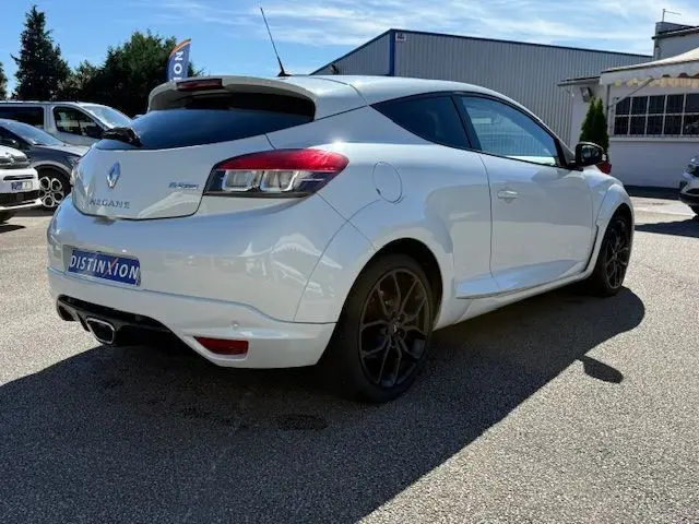 Renault Mégane III Coupé 2.0T 265cv RS blanc nacré vue 3/4 arrière droit avec jantes noires et échappement central.