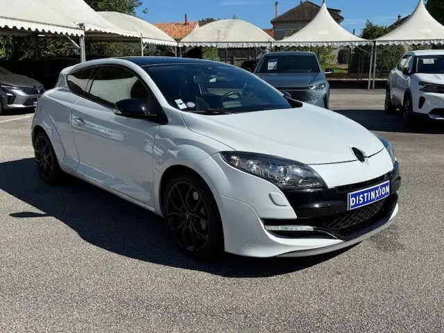 Profil droit d'une Renault Mégane III Coupé 2.0T RS blanc nacré avec jantes noires, stationnée en extérieur.