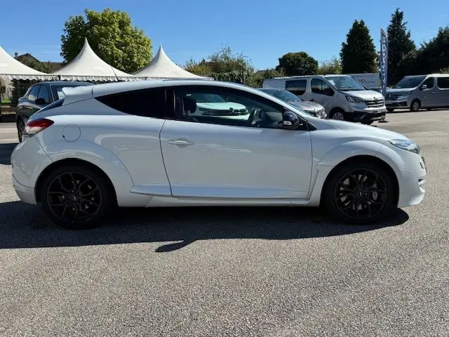 Vue 3/4 arrière droite d'une Renault Mégane III Coupé 2.0T RS blanc nacré avec jantes noires et double sortie d'échappement centrale.