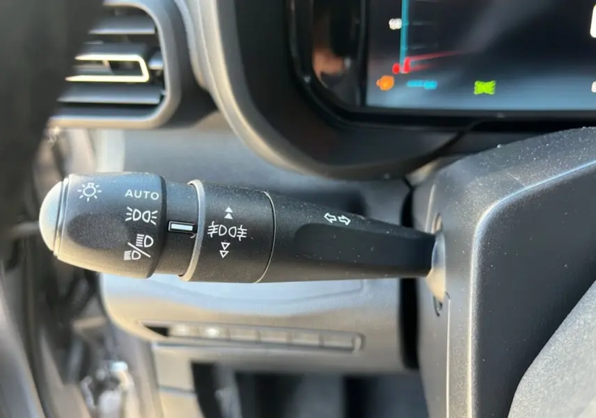 Gros plan sur la commande des feux et clignotants à gauche du volant dans l’habitacle du Citroën Berlingo gris 2025.