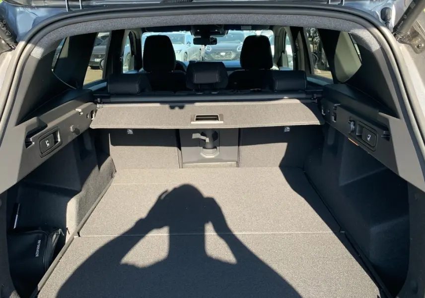 Vue intérieure du coffre ouvert du Dacia Bigster gris Schiste, montrant la tablette cache-bagages et les sièges arrière.