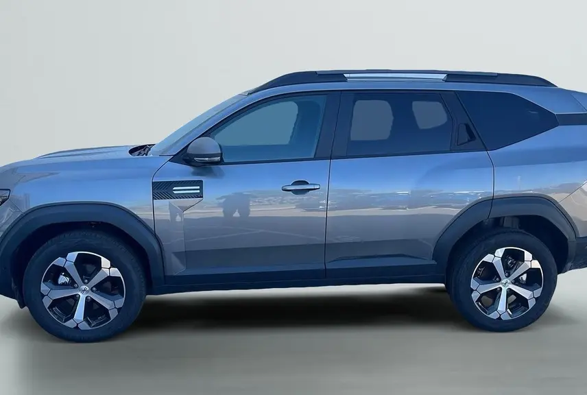 Vue de profil côté gauche du SUV Dacia Bigster 155 Journey gris schiste avec jantes alliage diamantées et barres de toit longitudinales.