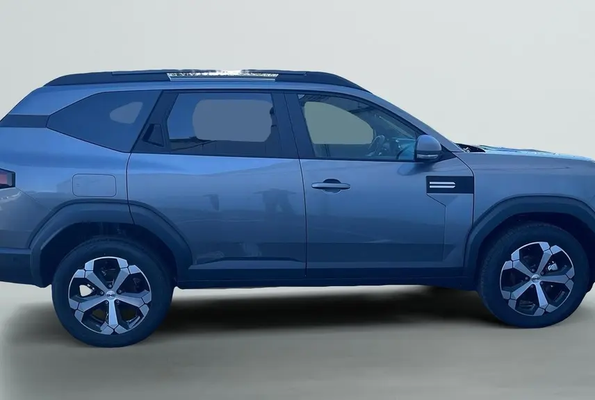 Profil droit du SUV Dacia Bigster 155 Journey gris schiste avec jantes alliage 18'' et barres de toit longitudinales.