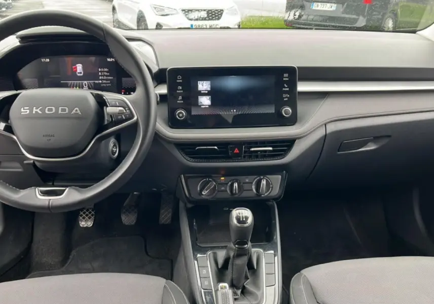 Intérieur de la Skoda Fabia 2025 vue de face, tableau de bord noir avec écran tactile et levier de vitesses manuel.