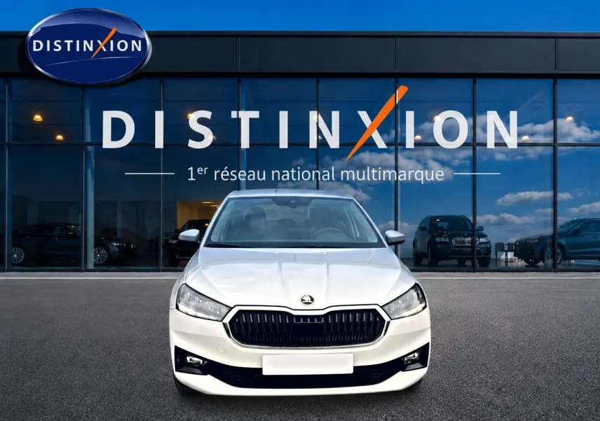 Vue avant d'une Skoda Fabia blanche 2025 avec calandre noire, stationnée devant une vitrine Distinxion.