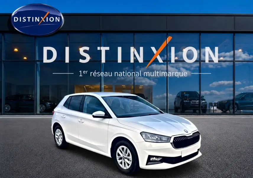 SKODA Fabia blanche vue en 3/4 avant droit, avec jantes alu et calandre noire devant un showroom Distinxion.