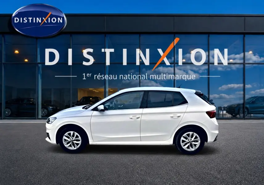 Profil côté gauche d'une Skoda Fabia blanche 2025 garée devant une vitrine avec logo Distinxion.
