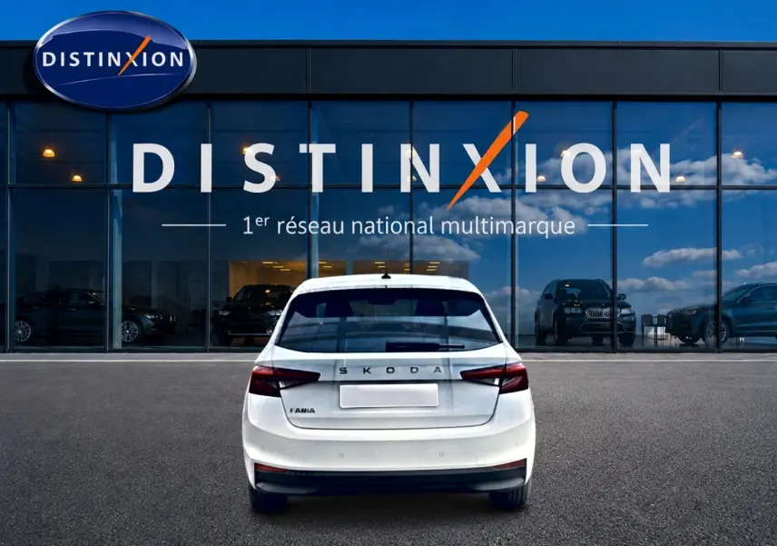 Vue arrière d'une Skoda Fabia blanche 2025 garée devant une vitrine avec logo Distinxion.