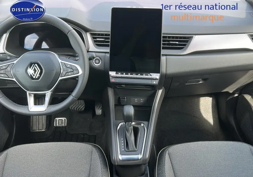 Vue intérieure avant du Renault Captur 2025 avec écran tactile vertical, volant multifonction et levier de boîte auto.