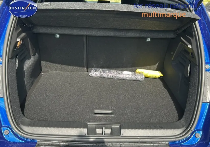 Coffre ouvert d’un Renault Captur bleu iron 2025, montrant un espace de rangement propre et spacieux.