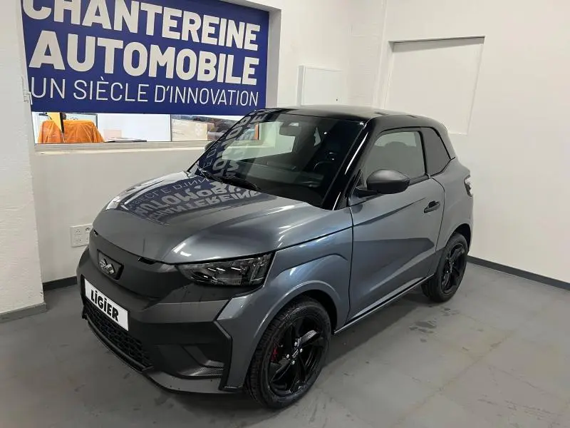 Vue 3/4 avant droite d'une Ligier JS50 Sport Elite E5+ gris métallisé avec jantes noires dans un showroom.