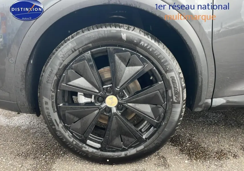 Gros plan sur la roue avant droite du DS7 gris titane, mettant en valeur la jante alu noire au design géométrique.