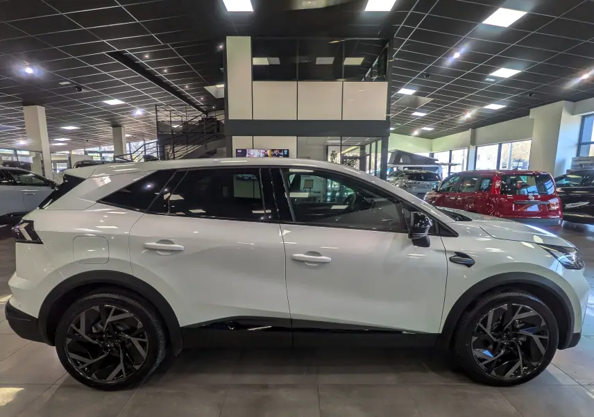 Profil côté gauche du Renault SYMBIOZ blanc nacré 2026 en hybride, avec jantes noires et détails noirs contrastants.