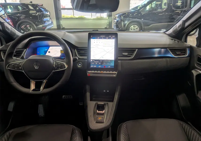 Vue intérieure avant du tableau de bord noir du Renault SYMBIOZ avec écran tactile vertical et volant multifonction.