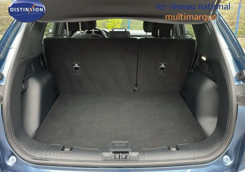 Vue arrière du coffre ouvert du Ford Kuga 2024 bleu vapor metal, montrant un espace de chargement propre et spacieux.