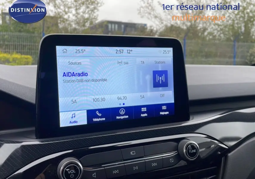 Écran tactile central du Ford Kuga 2024, affichant la radio et les options multimédia, avec tableau de bord noir.
