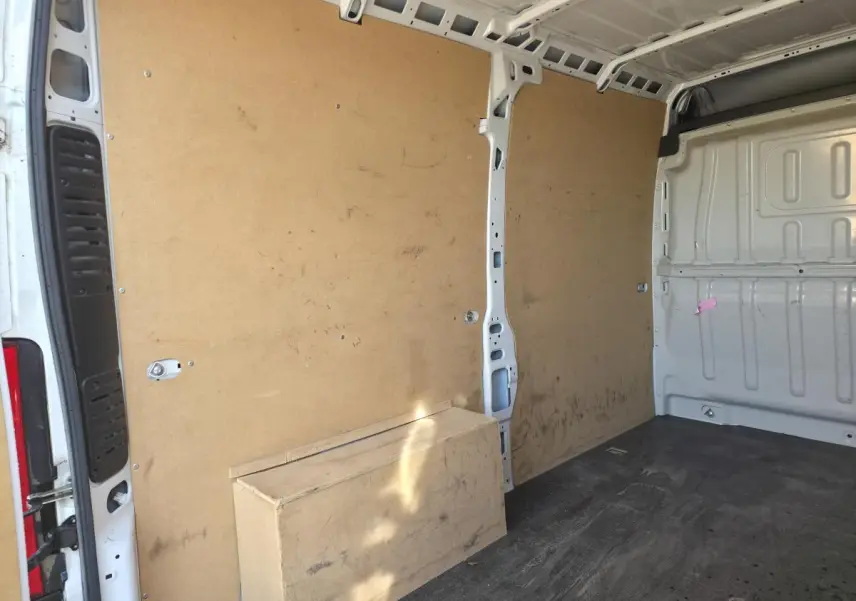 Vue intérieure arrière du fourgon blanc FIAT Ducato tôlé 3.5 M avec parois en bois et sol noir usé.