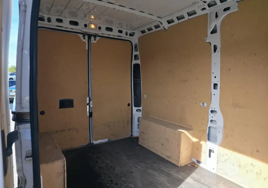Vue intérieure arrière du fourgon blanc FIAT Ducato tôlé 2023, montrant la cloison et le revêtement bois des parois.
