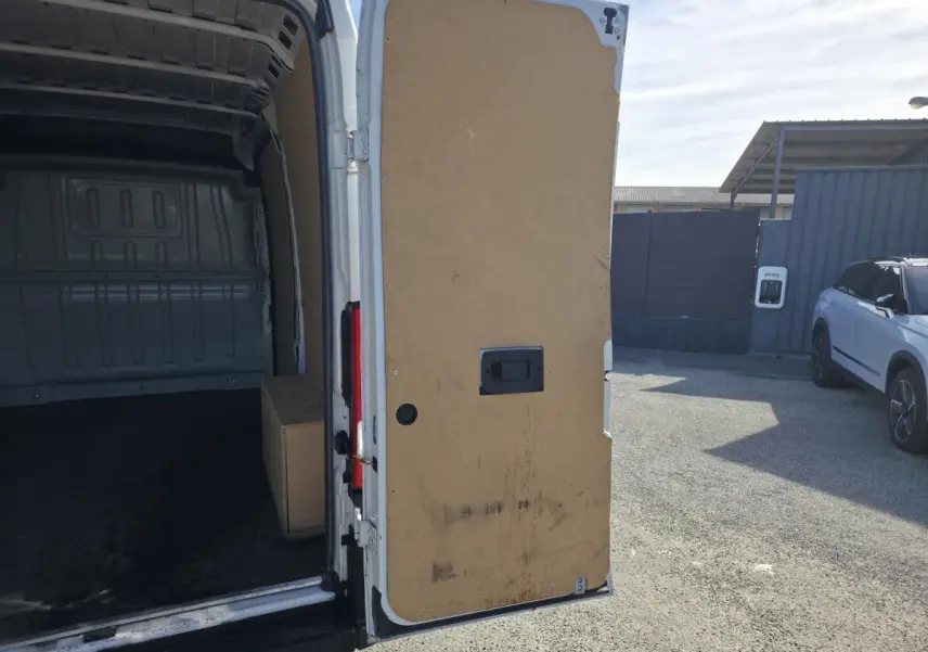 Vue arrière droite d'un FIAT Ducato Fourgon blanc 2023 avec porte arrière tôlée ouverte montrant l'intérieur vide.