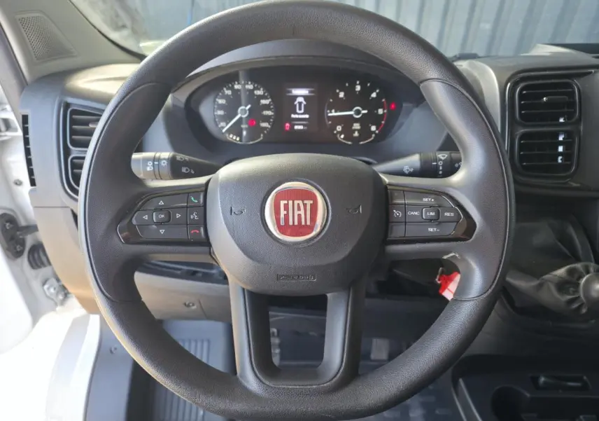 Vue frontale du volant noir du Fiat Ducato Fourgon 2023 avec commandes intégrées et tableau de bord visible.