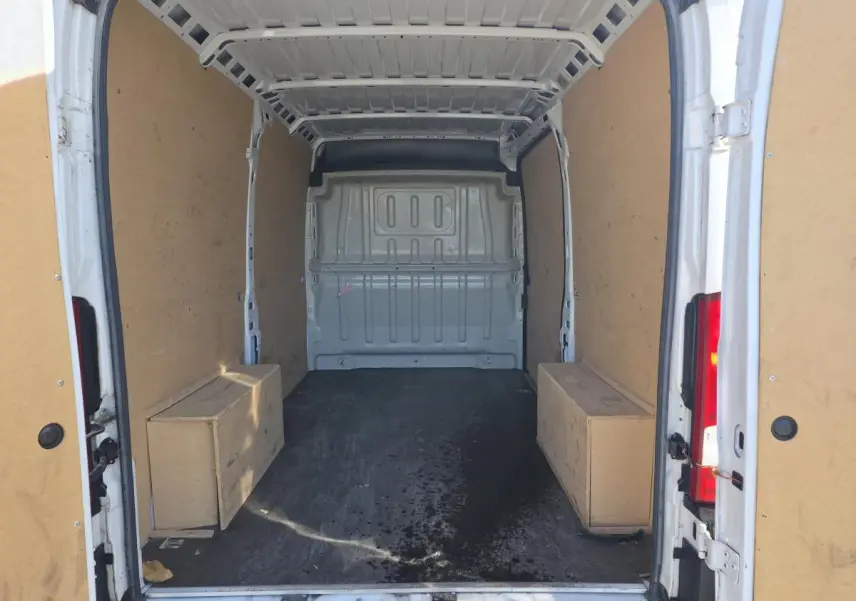 Vue arrière du fourgon blanc FIAT Ducato tôlé 3.5 M, montrant l’intérieur vide avec parois en bois et sol noir.