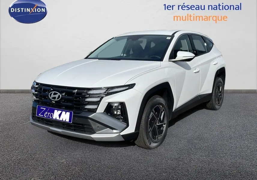 Vue 3/4 avant d'un Hyundai Tucson blanc Atlas 2026 avec jantes noires et calandre noire distinctive.