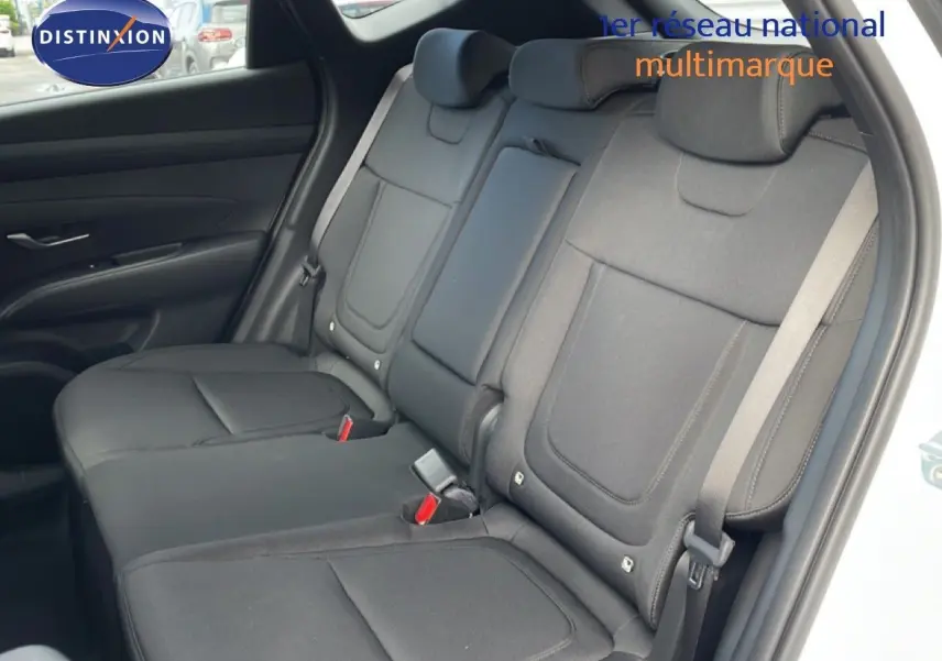 Vue intérieure montrant les sièges arrière noirs en tissu du Hyundai Tucson blanc Atlas, porte arrière ouverte côté droit.