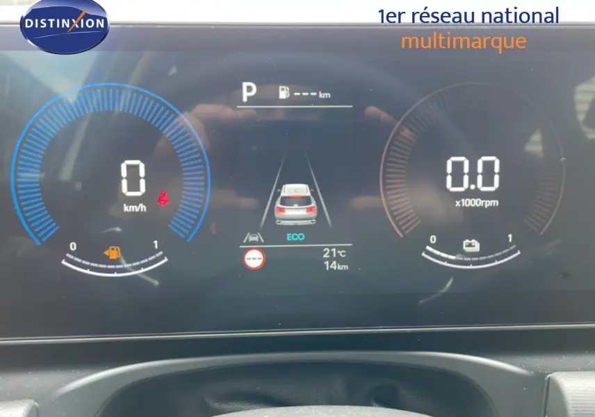 Tableau de bord numérique du Hyundai Tucson blanc, affichant vitesse, régime moteur et mode éco en vue frontale.
