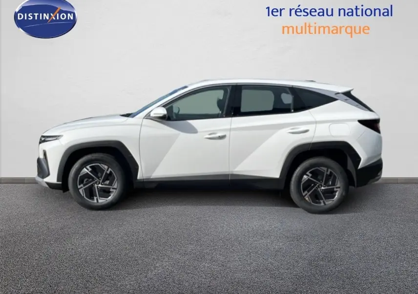 Vue de profil côté gauche d'un Hyundai Tucson blanc Atlas 2026 avec jantes bi-ton et lignes anguleuses marquées.