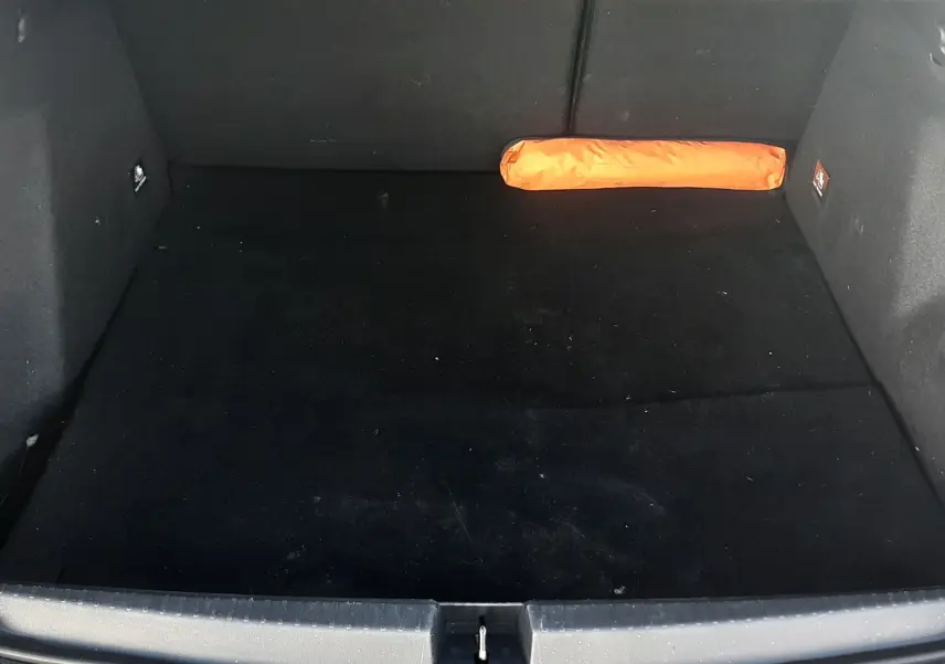 Coffre ouvert du Dacia Duster gris 2024, vue de dessus, avec un triangle de signalisation orange à droite.