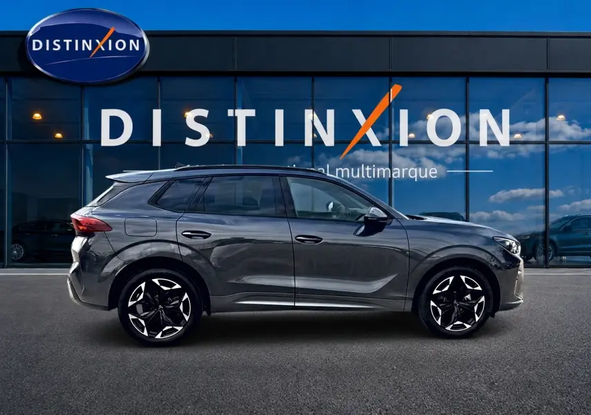 Vue latérale droite du CUPRA Terramar gris Timanfaya 2026 avec jantes noires et détails chromés, devant une vitrine Distinxion.
