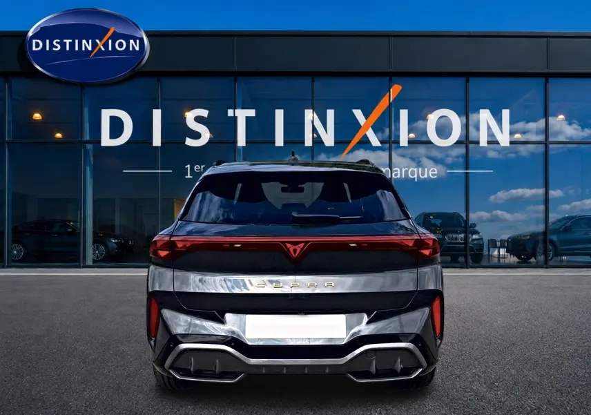 Vue arrière d'un CUPRA TERRAMAR gris timanfaya avec feux LED et diffuseur noir, stationné devant un showroom Distinxion.
