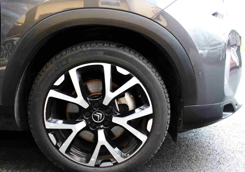 Gros plan sur la roue avant droite du Citroën C5 Aircross gris platinium, mettant en valeur la jante alliage bicolore au design moderne.